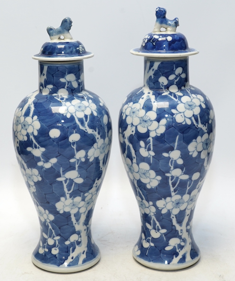 A pair of Chinese blue and white prunus baluster vases and covers, 31cm high. Condition - one vase good, the other pieces poor